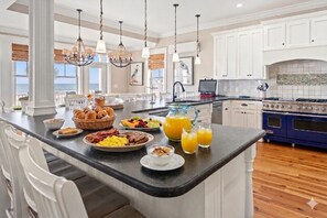 A kitchen with a breakfast bar, white cabinets, a blue stove, and a view of the ocean. - Diamond in the Ruff - Total Luxury 8BR OF Home (North Myrtle Beach)