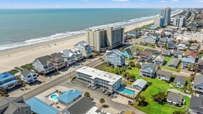 A coastal residential area with beachfront properties, a large hotel, and a swimming pool.