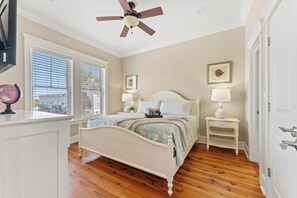 A bedroom with a bed, bedside tables, a ceiling fan, and a window with blinds.