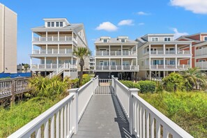 A multi-story residential building with balconies, a wooden walkway, and surrounding greenery. - Diamond in the Ruff - Total Luxury 8BR OF Home (North Myrtle Beach)