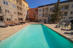Relax by the pool surrounded by a spacious deck with lounge chairs and a table.