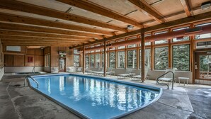 An indoor swimming pool with wooden beams and large windows.