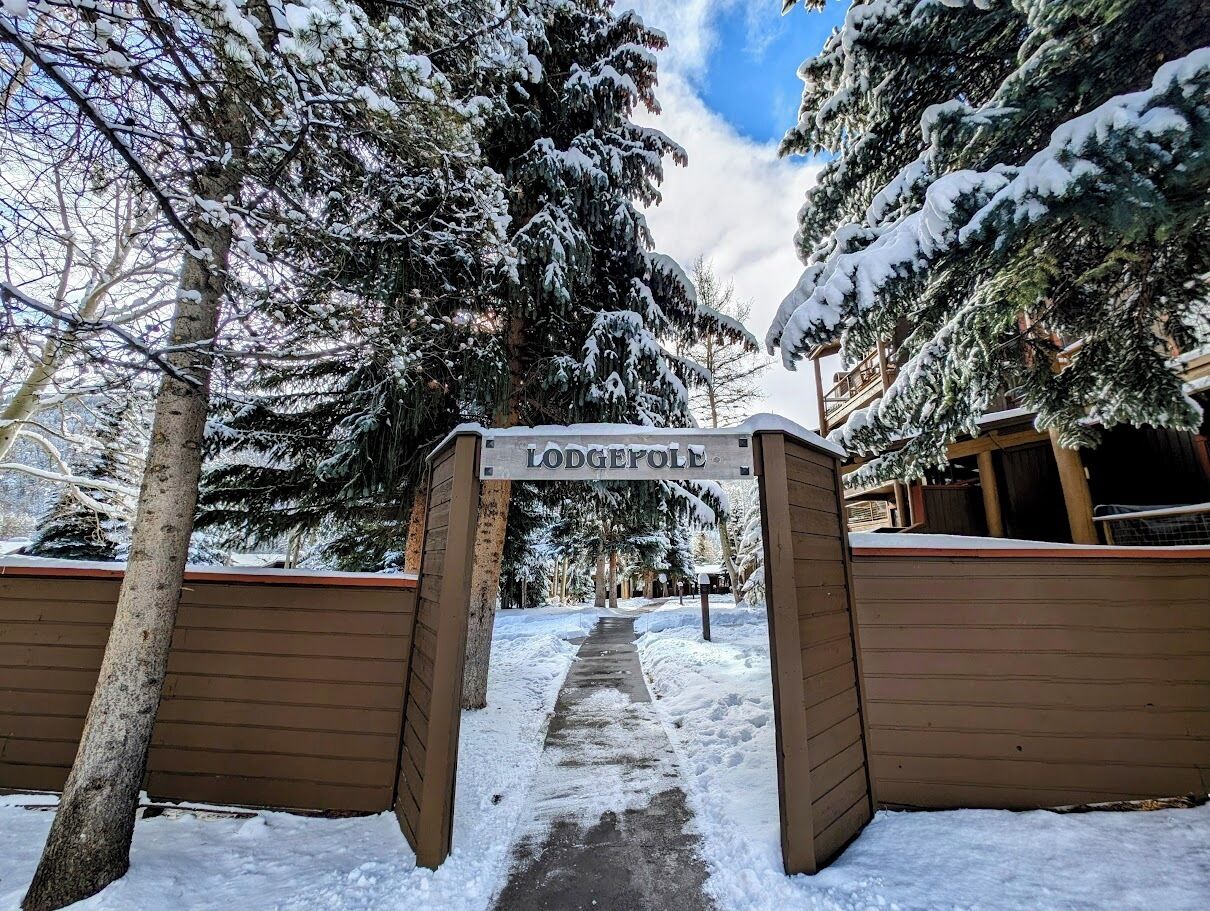 A snow-covered pathway leading to a lodge entrance with a sign reading "Lodgepole."