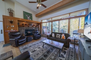 A spacious living room with a fireplace, leather sofas, a coffee table, and a large window offering a view of the outdoors. - Lodgepole 2011 (Keystone)