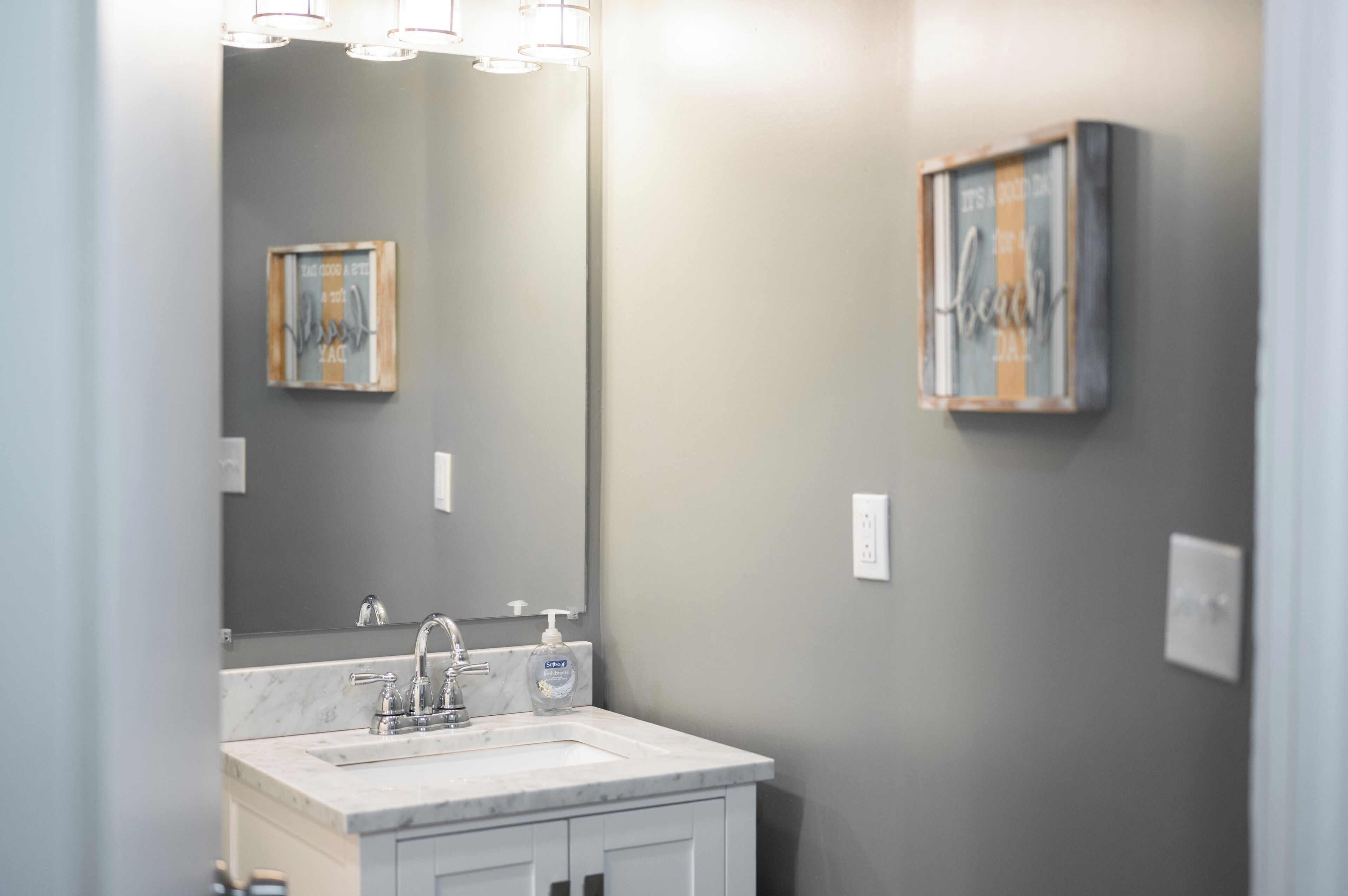 A bathroom with a marble sink, a large mirror, and two wall-mounted light fixtures.