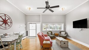 A spacious living room with a dining area, a ceiling fan, a television, and a large window with curtains. - Tandem Suite - Spacious 2 Bedroom Suite Walkable to Downtown TC (Traverse City)