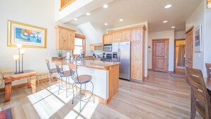 A spacious kitchen with wooden cabinets, a central island with bar stools, and a dining area with a table and chairs. - Antlers Gulch 502 (Keystone)