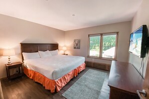 A bedroom with a large bed, two bedside lamps, a window with a view, and a TV on the wall. - Black Bear 8055 (Keystone)