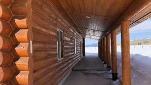 Une cabane en rondins avec un long couloir, des poutres en bois et des fenêtres.
