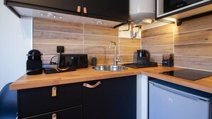 A compact kitchen with a wooden countertop, a built-in sink, a microwave, and a small refrigerator. - THE SQUARE ROOT (Dijon)