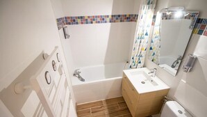 A bathroom with a bathtub, a sink, a toilet, and a shower curtain. - THE SQUARE ROOT (Dijon)