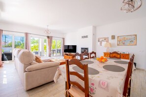 Una sala moderna con sofá, mesa de comedor y televisor.