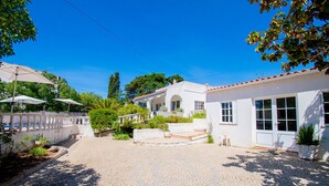 A courtyard with cobblestone paving, a white building with a tiled roof, and a white fence. - Montenegro Superbly Located Family Vila With Game Room & Pool (Carvoeiro)