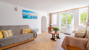 A living room with a grey sofa, a beige armchair, a wooden coffee table, and a painting on the wall. - Montenegro Superbly Located Family Vila With Game Room & Pool (Carvoeiro)