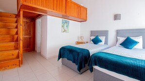 A room with two beds, wooden flooring, a painting on the wall, and a staircase. - Montenegro Superbly Located Family Vila With Game Room & Pool (Carvoeiro)
