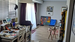 Ampla sala de estar com mesa de jantar, cadeiras, um quadro grande e ventilador de teto.