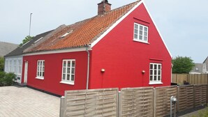 Une maison rouge avec un toit en pente et des fenêtres blanches.