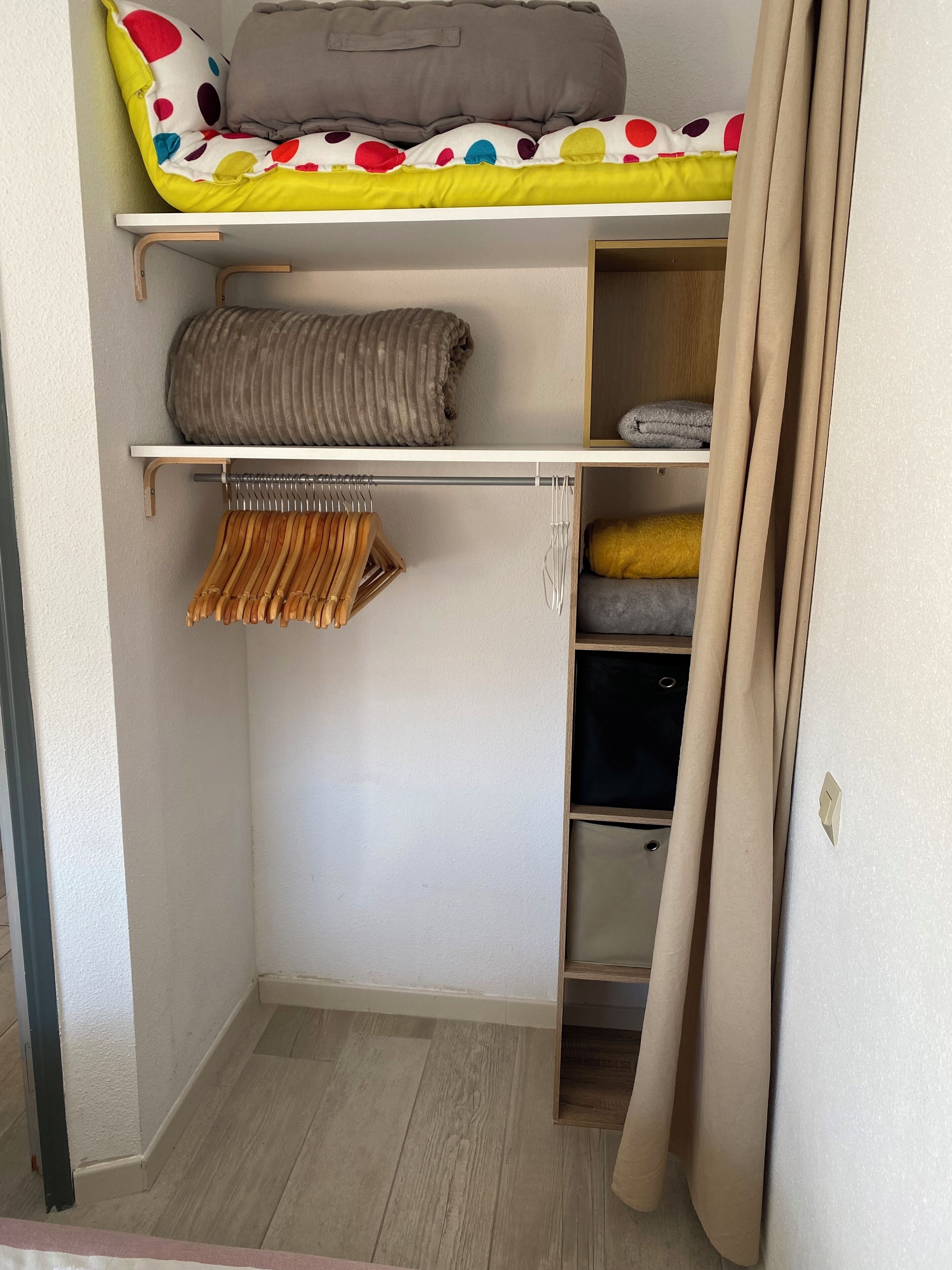 Une petite pièce comprenant un lit superposé, une armoire et une petite étagère.