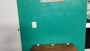 A teal wall with a wooden bench, a white door, and a painting of a sailboat on the beach. - Vacation home (Isla Mujeres)