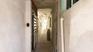 A narrow corridor with a concrete floor, white walls, and a door on the left. - Vacation home (Isla Mujeres)