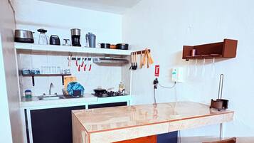 Una cocina compacta con una isla central, taburetes y una variedad de utensilios de cocina.