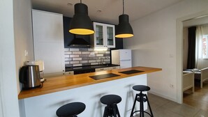 A modern kitchen with a wooden countertop, black bar stools, and pendant lighting. - Beach House Villa Antares, Penthouse apt. A1 (Pisak)