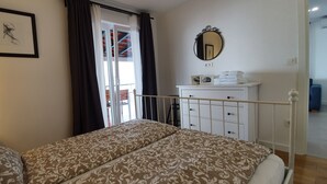 A bedroom with a bed, a bedside table with a lamp, a dresser, a mirror, and a door leading to a balcony. - Beach House Villa Antares, Penthouse apt. A1 (Pisak)
