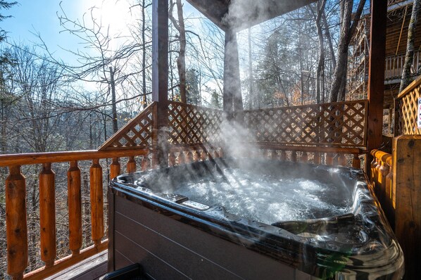 A hot tub on a wooden deck with a view of a forested area.