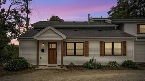 A single-story house with a front porch, a wooden door, and two windows with shutters. - Walk Downtown | Parkside | City View | Beautifully Remodeled (Ann Arbor)