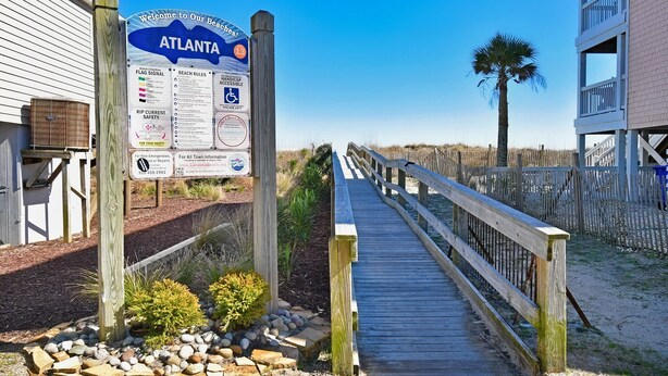 A wooden boardwalk leading to a beach area with a signboard displaying beach rules and safety information. - Blue Heaven - Walk to Beach & Boardwalk, Ocean and Sunset Views, Dog-Friendly (Carolina Beach)