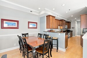 A modern kitchen with wooden cabinets, a central island, and a dining area with a wooden table and chairs.