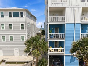 A multi-story residential building with a balcony and a car parked in the garage.