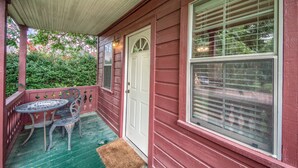 A porch with a table and chairs, a white door, and a window with blinds. - 1 mile to downtown - Short Drive - Jacuzzi Bath (Fredericksburg)