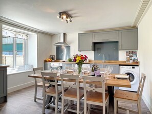 A modern kitchen with a dining area, a washing machine, and a window with a view. - Wingate Farm near Countisbury (Nr Lynton)