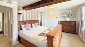 Une chambre à coucher avec un lit en bois, une commode, une lampe et un luminaire fixé au mur.