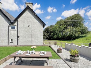 A dining table set outdoors with a view of a house and a grassy hill. - Wingate Farm near Countisbury (Nr Lynton)
