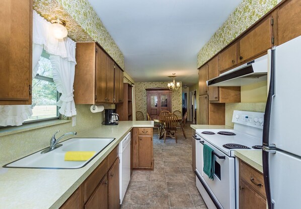 A compact kitchen with wooden cabinets, a white stove, and a sink.