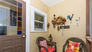 A cozy corner with wicker chairs and a small table, a window with blinds, and a wall decorated with farm-themed ornaments.