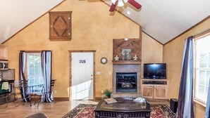 A spacious loft-style living room with a high ceiling, a fireplace, a television, and a dining area with a table and chairs. - Private Hot Tub - Fireplace - 4 min. to downtown - Wildlife (Fredericksburg)