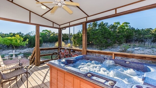 A hot tub area with a wooden deck, a ceiling fan, and bicycles leaning against the railing. - Private Hot Tub - Fireplace - 4 min. to downtown - Wildlife (Fredericksburg)