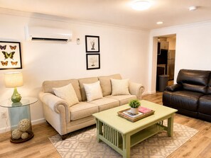 A living room with a beige sofa, a green coffee table, and a black leather chair.