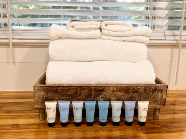 A wooden box with folded towels and a row of H2O therapy products. - Cottage 3 - Back Bay Bungalow (Fairhope)
