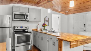 Una cocina moderna con electrodomésticos de acero inoxidable, techo de madera y encimera de madera.
