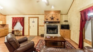 Ein gemütliches Wohnzimmer mit Kamin, Ledersofas, einem Holztisch und einem Deckenventilator.