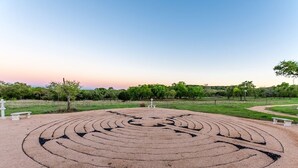 Ein Labyrinth in einem Park mit Bänken und Bäumen im Hintergrund.