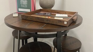 A round table with a lamp, a tray with items, and a framed sign.