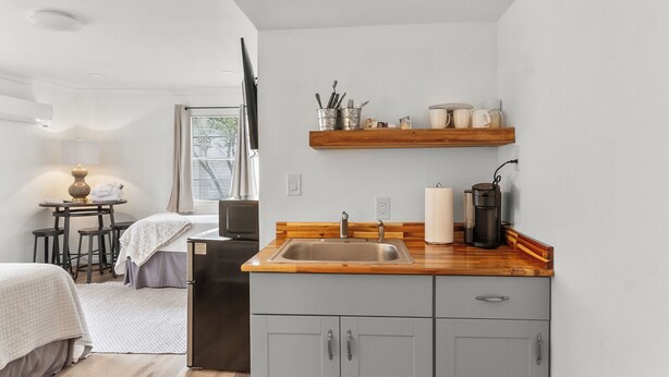 A compact kitchen with a sink, wooden countertop, and a built-in stove. There is a small dining area with a table and chairs.