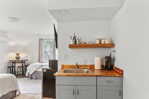 A compact kitchen with a sink, a coffee maker, and a wooden countertop.