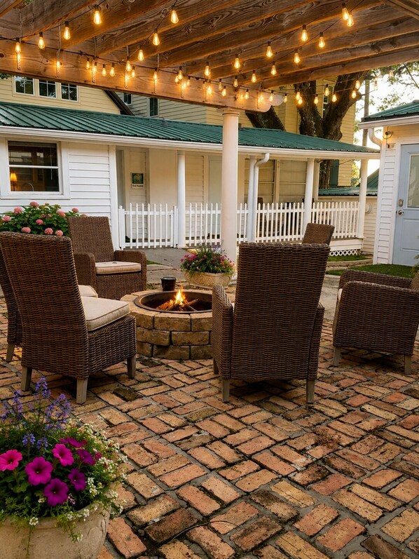 An outdoor patio with wicker furniture, a fire pit, and string lights.