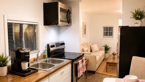 Une cuisine compacte équipée d’une cuisinière, d’un évier et d’un four à micro-ondes. Un coin repas avec une table pour deux personnes est également disponible.